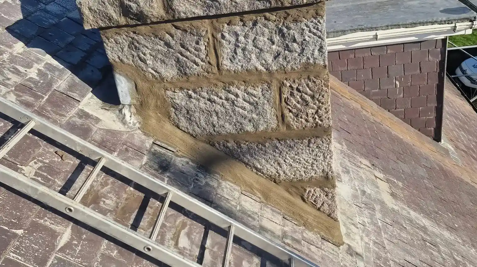 Granite chimney stack with fresh mortar joints and new flaunching around two chimney pots