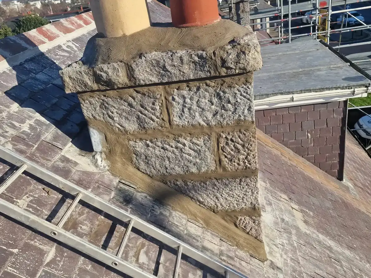 Granite chimney stack with fresh mortar joints and new flaunching around two chimney pots