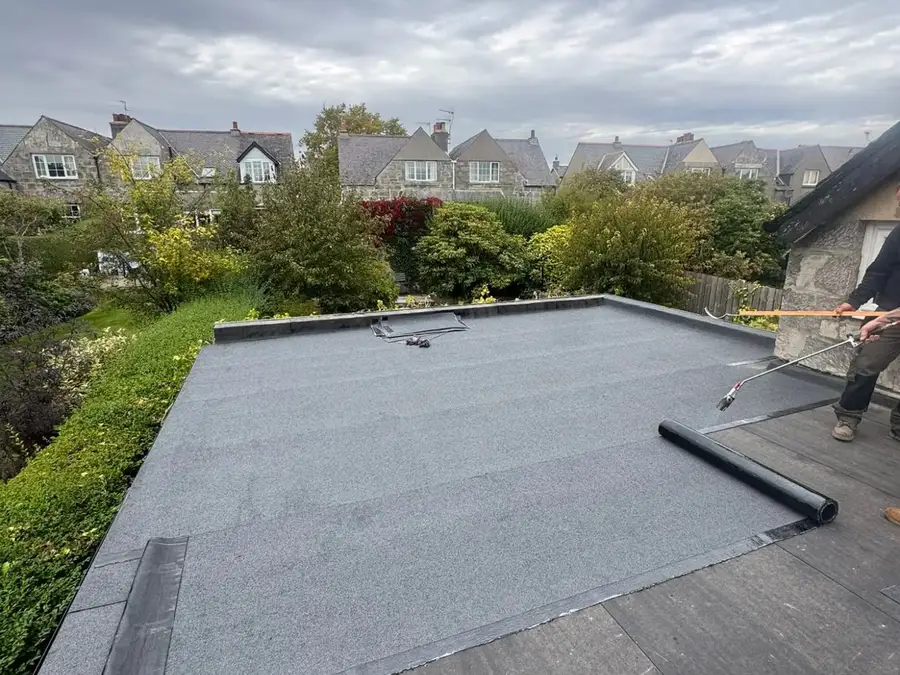 A new roll of flat roof covering being laid