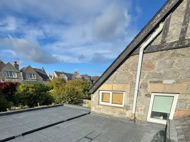 A finished flat roof beside a stone gable wall
