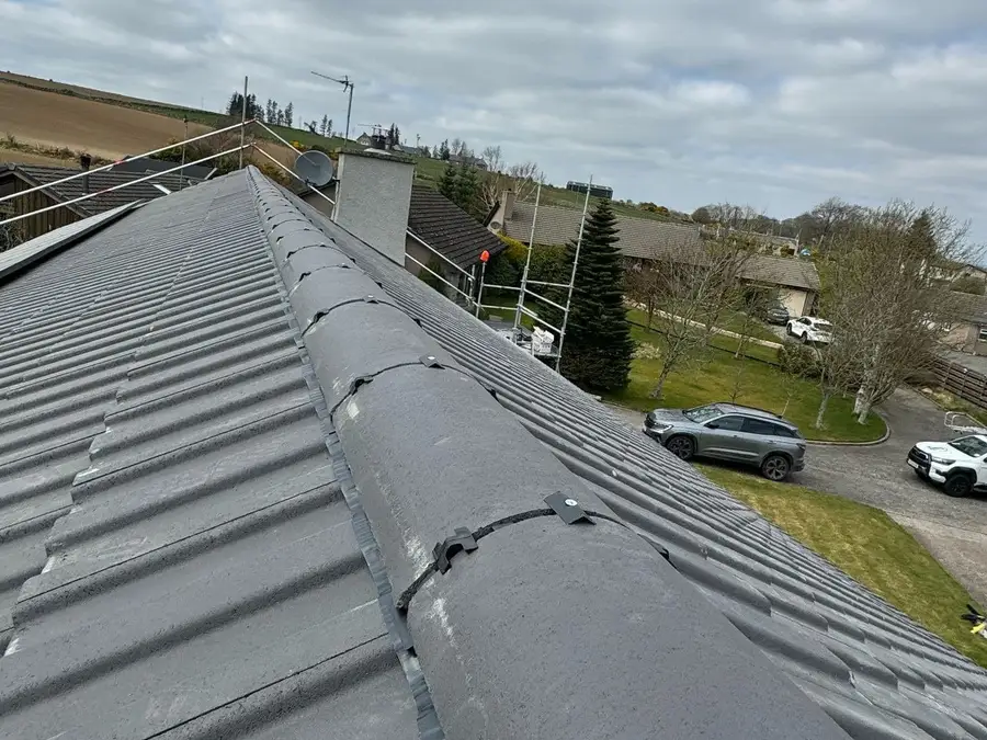 Ridge tiles held with clips and screws along a newly tiled roof
