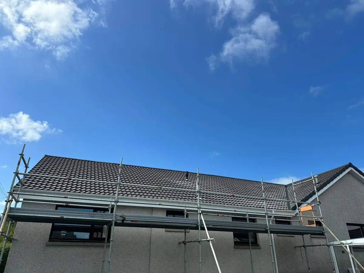 Scaffold along a house with a newly tiled dark roof
