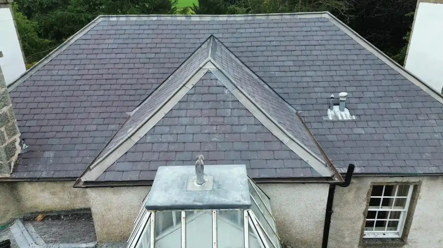 Lead-covered hips on a slate roof meeting above a glass roof lantern