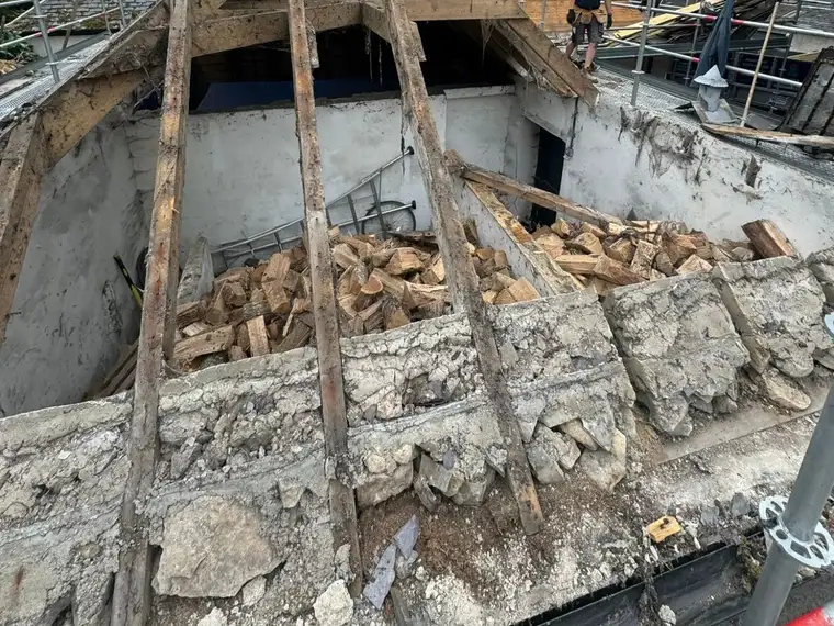 An old hipped roof stripped back to its timbers inside a scaffold